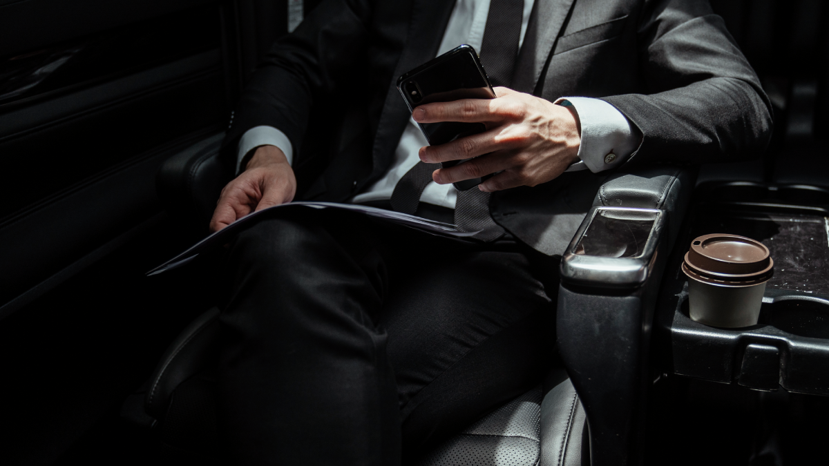 Professional chauffeur standing beside a luxury black car in Denver, ready for private or business transport